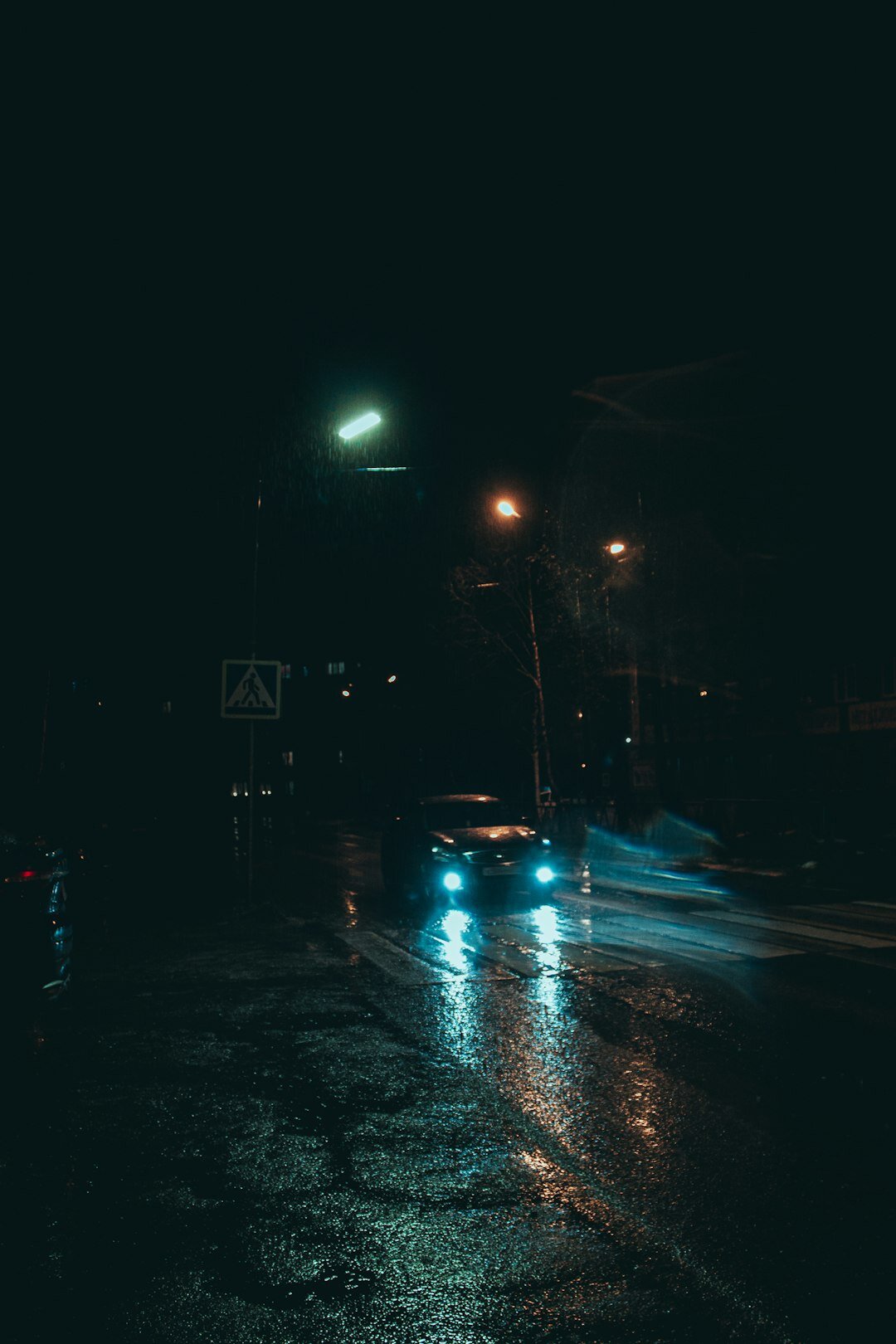 Rainy city street at night with a lit lamp post