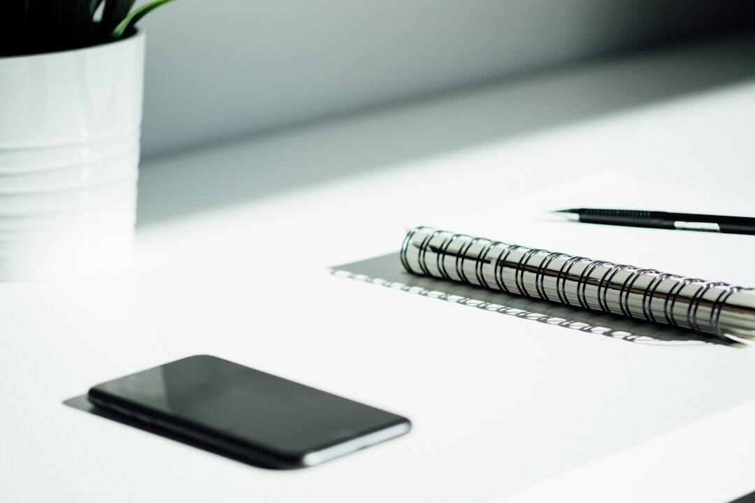 Modern desk with notebook, pen and phone